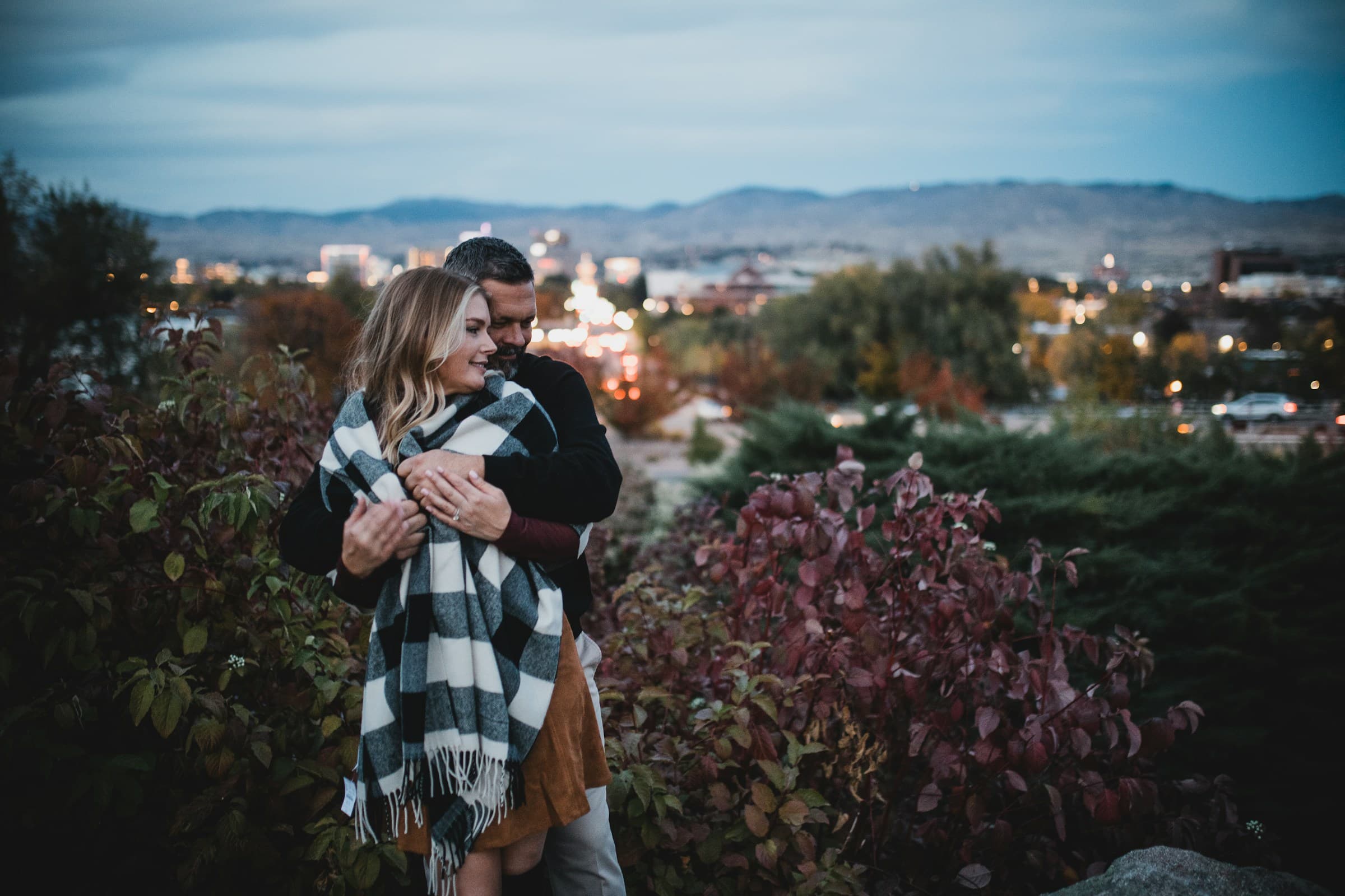 A couple embracing with the Boise skyline and foothills behind them